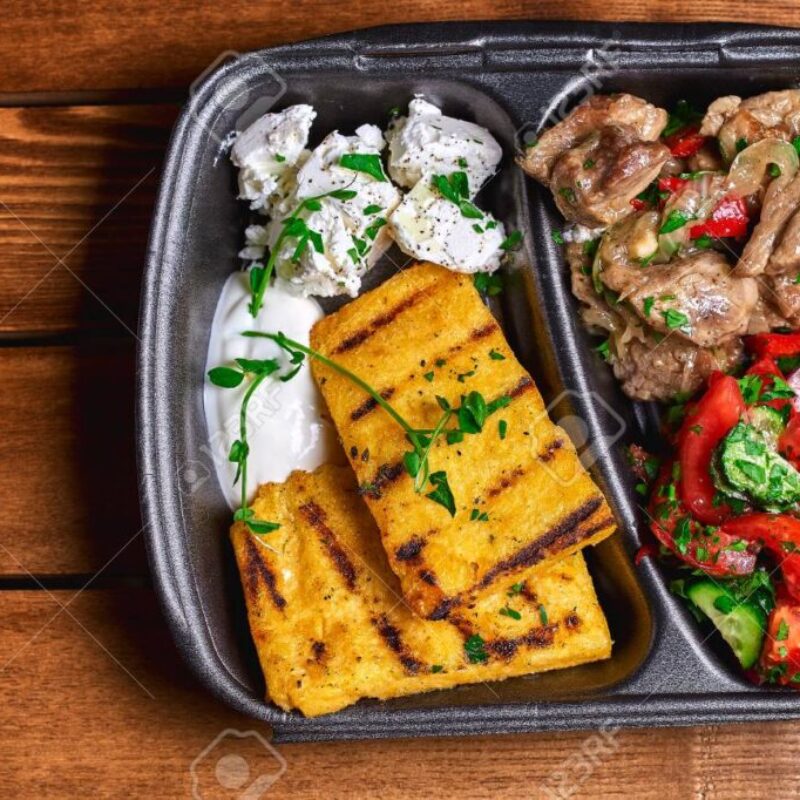 Hominy with meat stew pork, beef and salad in plastic dishes. Street food. Free space for text.